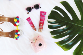 Overview of colorful shoes, self-tanner, sunglasses, and camera.